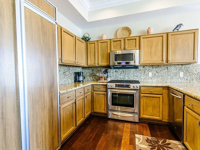 Granite kitchen with built-in refrigerator and gourmet gas stainless steel oven range.