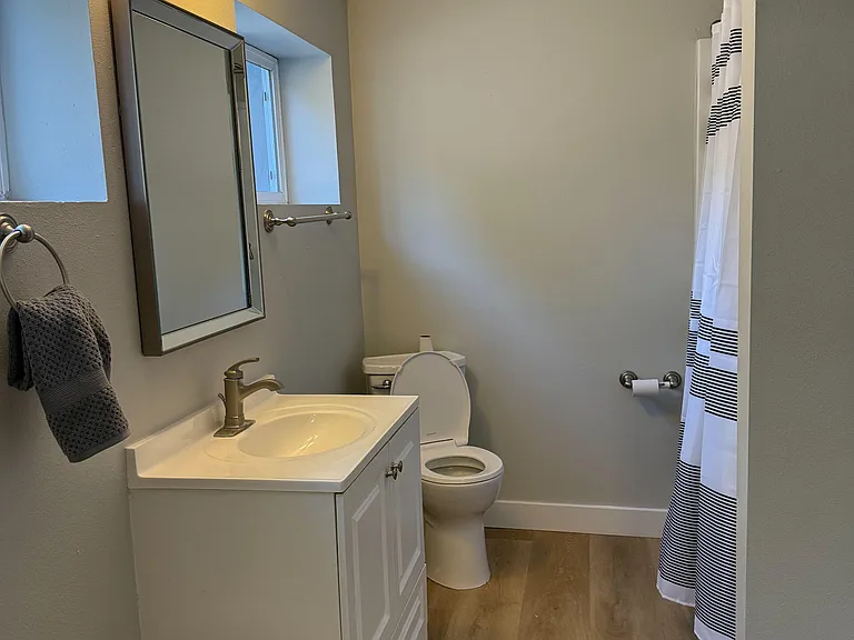 Clean full bath with single-sink vanity, framed mirror, and tub/shower with curtain; window adds natural light.