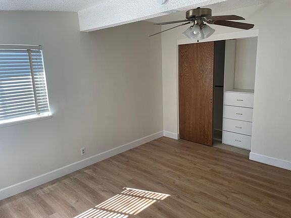 Master bedroom with closet organizer, attached bathroom, and ceiling fan