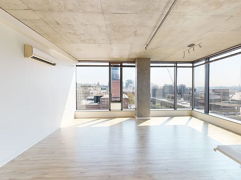 Apartment living room with wood-style flooring and floor-to-ceiling windows.