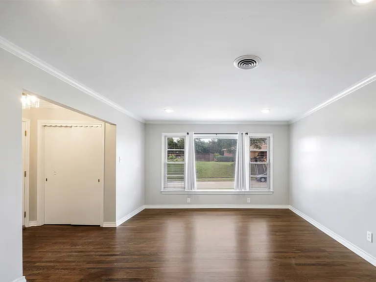 Empty room featuring dark hardwood / wood-style floors and ornamental molding