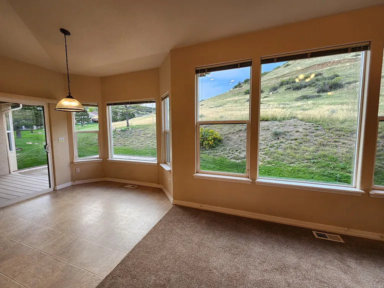 View from Dining Nook off Kitchen and Family Room to Open Space. The sliding glass door on the left opens to a covered deck.