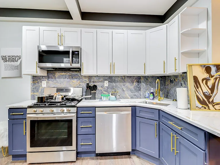 Updated kitchen with stainless steel appliances, ample shaker cabinetry, and generous counter space with a corner sink.