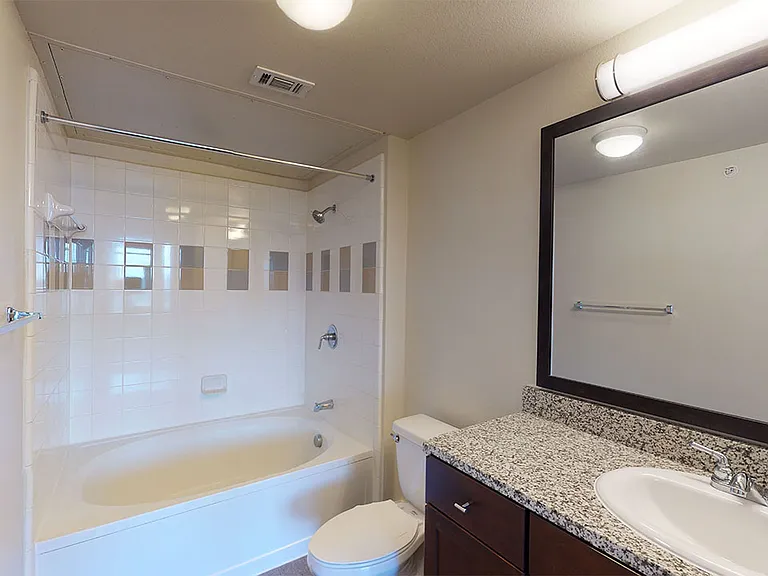 Apartment bathroom with large soaking tub and wood-style flooring.