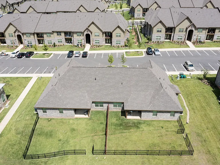Aerial view of a modern apartment community showcasing beautiful green spaces and ample parking, perfect for urban living.