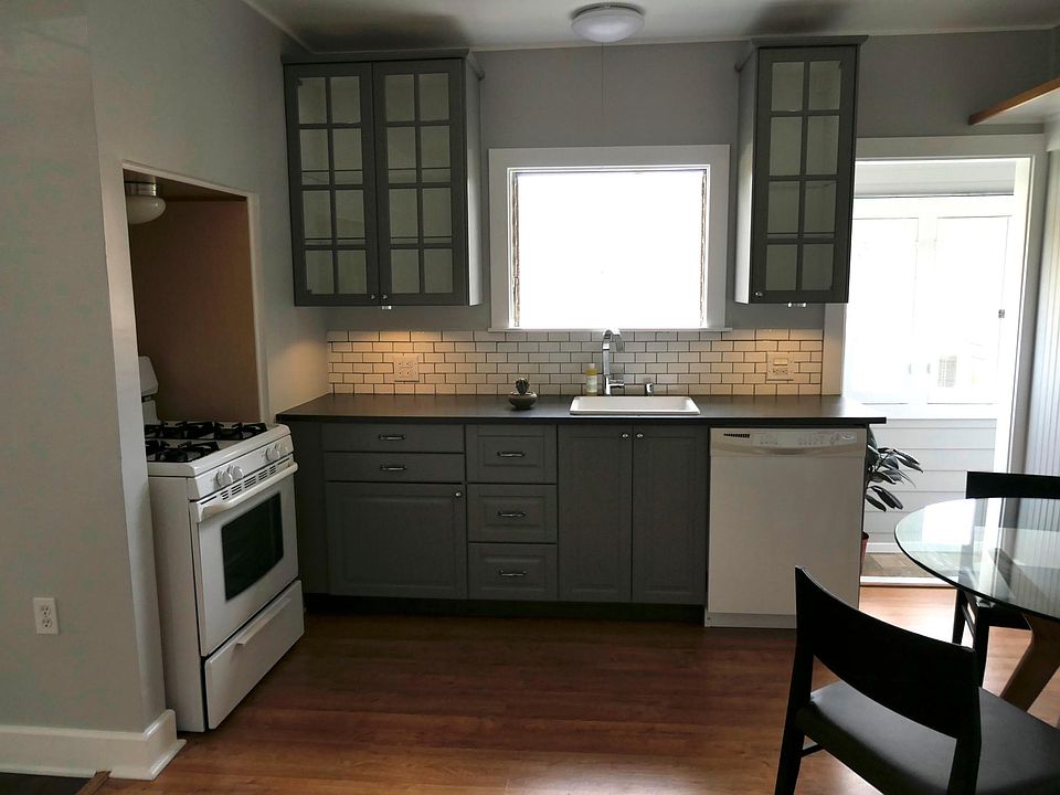 Recently remodeled kitchen with laundry porch entry on the right. Refrigerator, stove, dishwasher, and stack clothes washer dryer on enclosed porch.