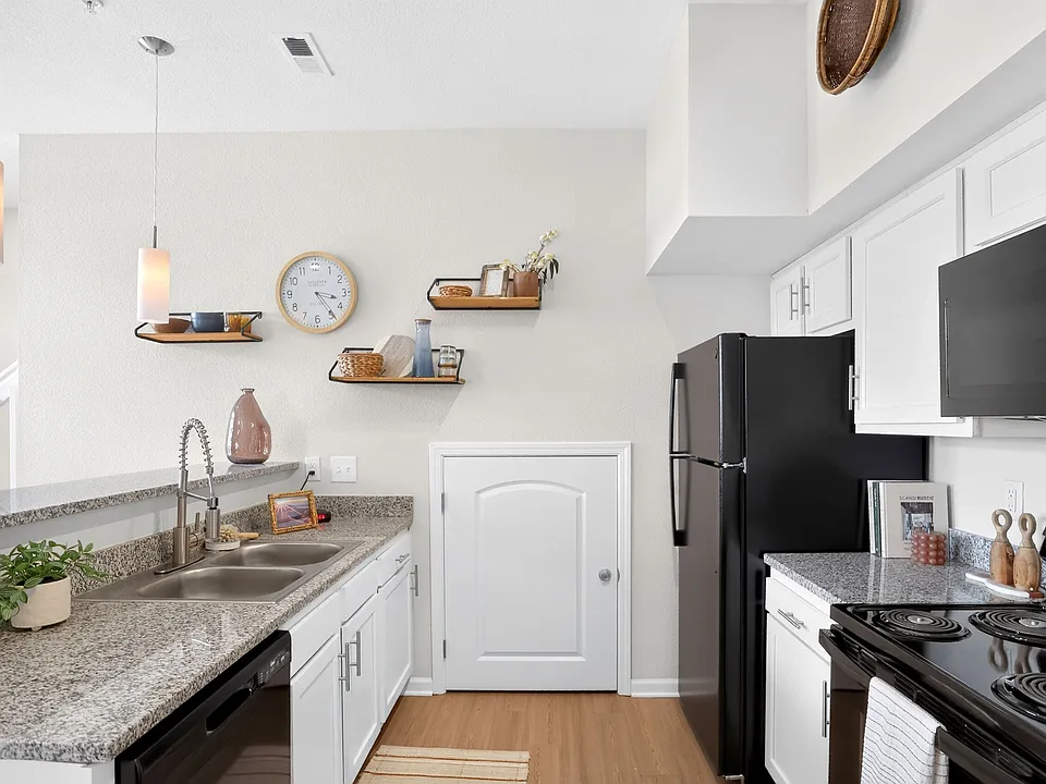 Modern kitchen with granite countertops, sleek black appliances, and stylish open shelving, perfect for culinary creativity.