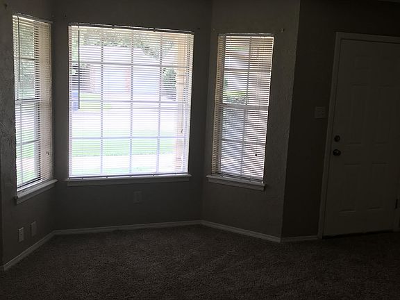 Living room has taupe walls with white trim, bay window with