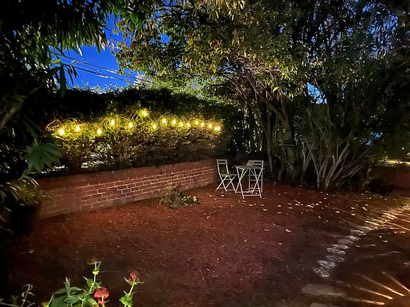Fairly lights at night by table and chairs in front of the house.