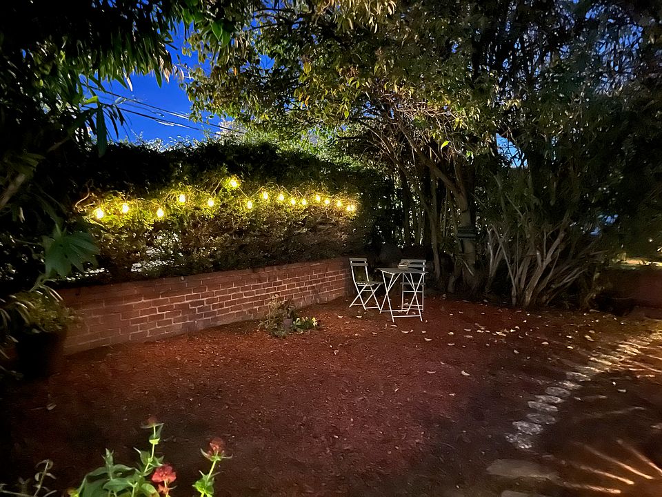 Fairly lights at night by table and chairs in front of the house.