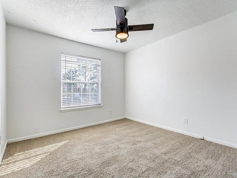 A carpeted bedroom with oversized closet and ceiling fan is shown at ReNew on Cantrell.