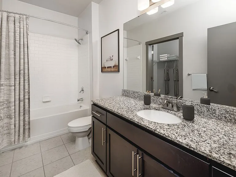 Classic Package II Bath with speckled granite countertop, dark wood cabinetry, and tile flooring