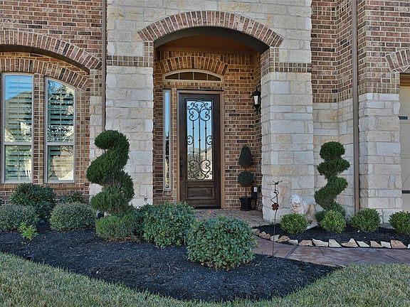 Stamped concrete walkway leads to your brick front porch w/ 3/4 glass mahogany front door with iron framing.