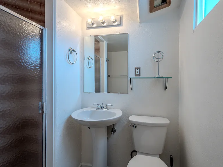 Basement bathroom with updated fixtures, tiled shower stall with glass door. Frosted privacy window. Spacious and clean.