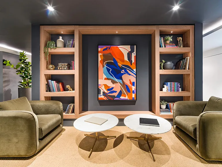 A thoughtfully designed lounge at Modera Aventura, where custom shelving, curated artwork, and layered textures create a polished setting for conversation or quiet focus.
