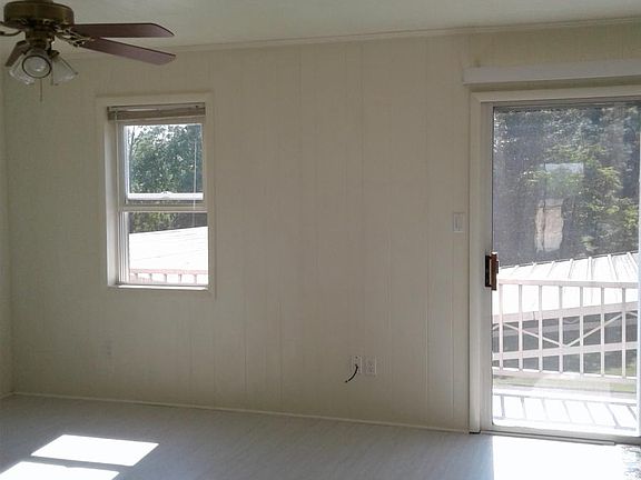 Living room with ceiling fan. Sliding door leads to a back p