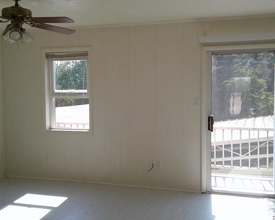 Living room with ceiling fan. Sliding door leads to a back p