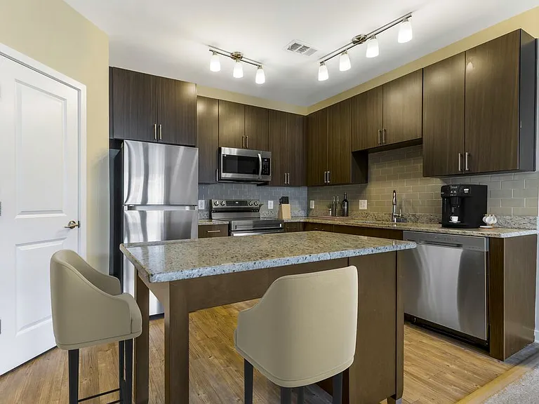 Upgraded kitchen with espresso cabinetry, grey speckled granite countertops, light grey tile backsplash, stainless steel appliances, and hard surface flooring