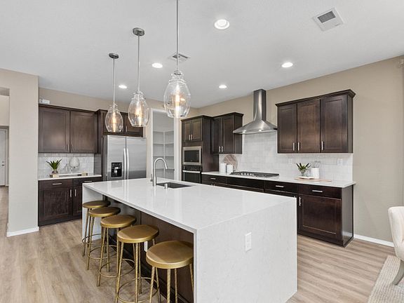 Enjoy a chef s kitchen with built-in stainless-steel appliances and hanging pendant lights abouve th