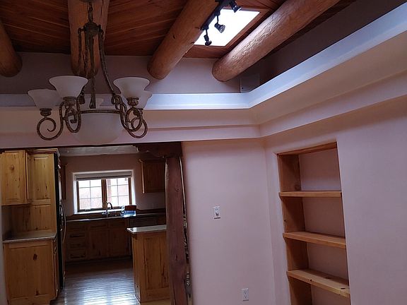 view of kitchen from dinning room. Vigas on ceiling with skylights. all walls are plastered finished