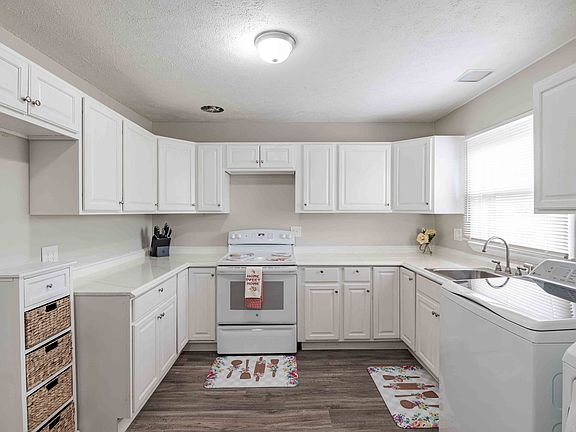a kitchen with white cabinets and a sink and a stove