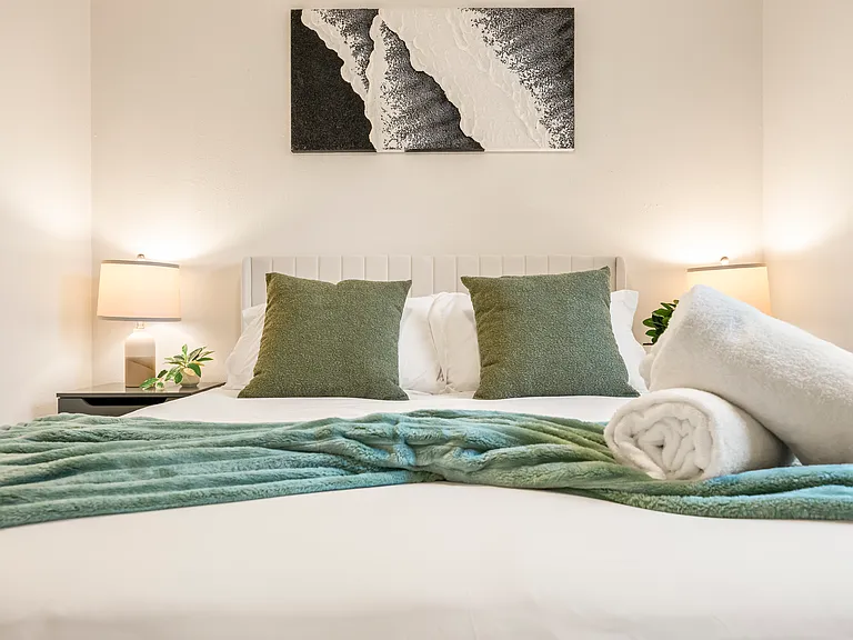 Cozy bedroom with a queen bed, ceiling fan, soft lighting, and comfortable accommodations designed for restful nights after exploring San Diego.
