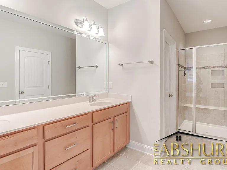 Owner's bathroom with dual vanity cultured marble countertops, tile walk in shower w/ bench