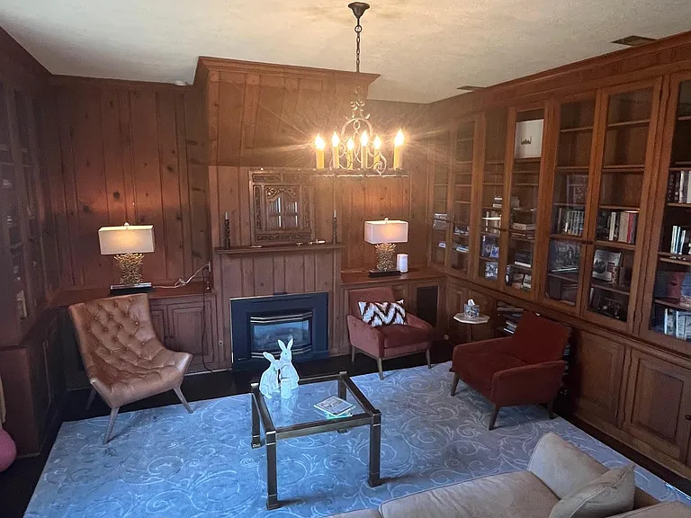 Wood-paneled library with wrap-around bookcases and gas fireplace
