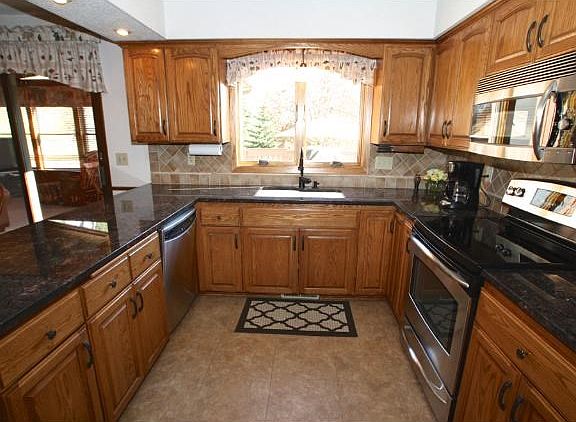 Updated kitchen featuring granite tops, stainless appliances, ample cabinetry plus a window overlooking the back area.