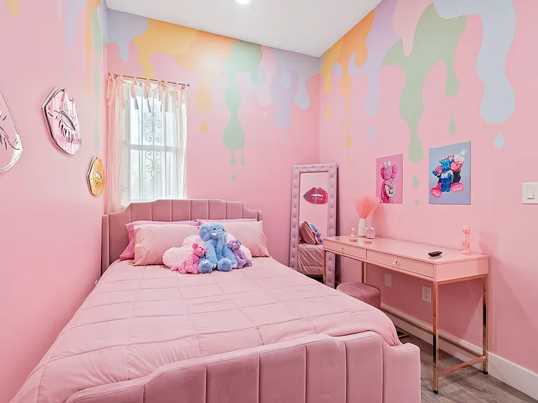 Furnished bedroom with a full bed, upholstered headboard, window with sheer curtains, and a dedicated desk/vanity area.