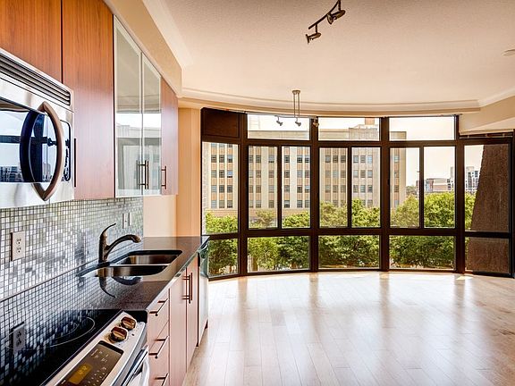 Kitchen with granite countertop, stainless steel appliances, designer backsplash, hard surface flooring and floor to ceiling windows