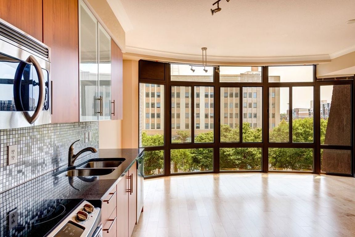 Kitchen with granite countertop, stainless steel appliances, designer backsplash, hard surface flooring and floor to ceiling windows