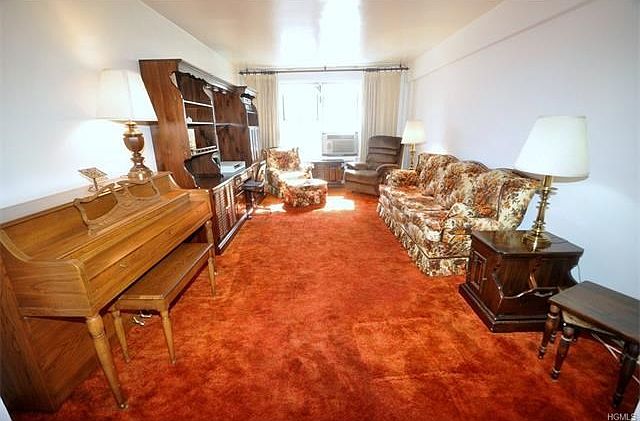 Large Sunny living room has covered hardwood floors and opens to the dining foyer.