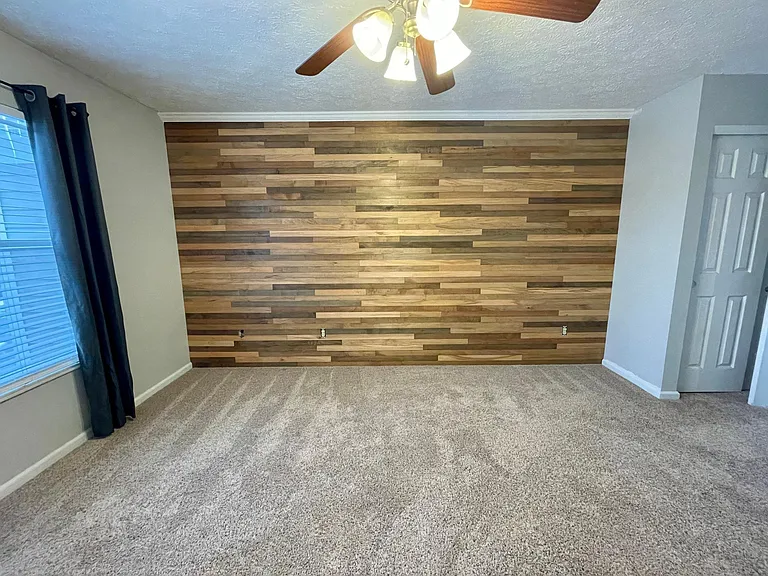 Spacious master bedroom with a gorgeous wood accent wall and ensuite bathroom.