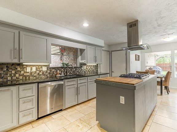 Updated kitchen with attractive backsplash, granite and granite tile on the cook island with fashionable fan vent.