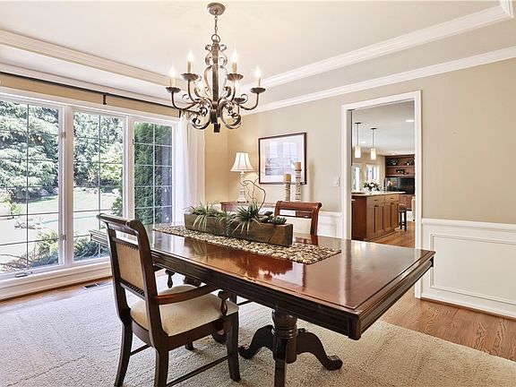 Formal dining room with wainscoting, crown molding, tray ceiling and wall of windows. Perfect for hosting special celebrations and holiday meals.