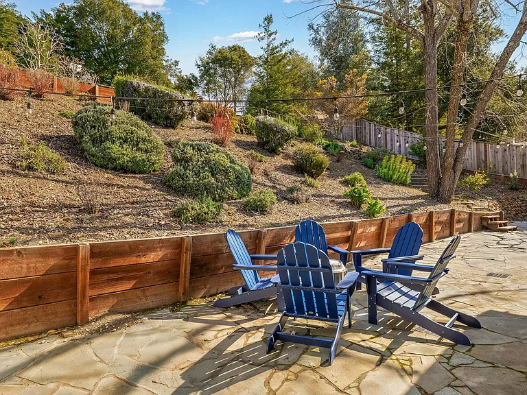 Peaceful patio vibes surrounded by natural landscaping, this sunny backyard retreat is perfect for morning coffee, evening chats, or stargazing from Adirondack chairs.
