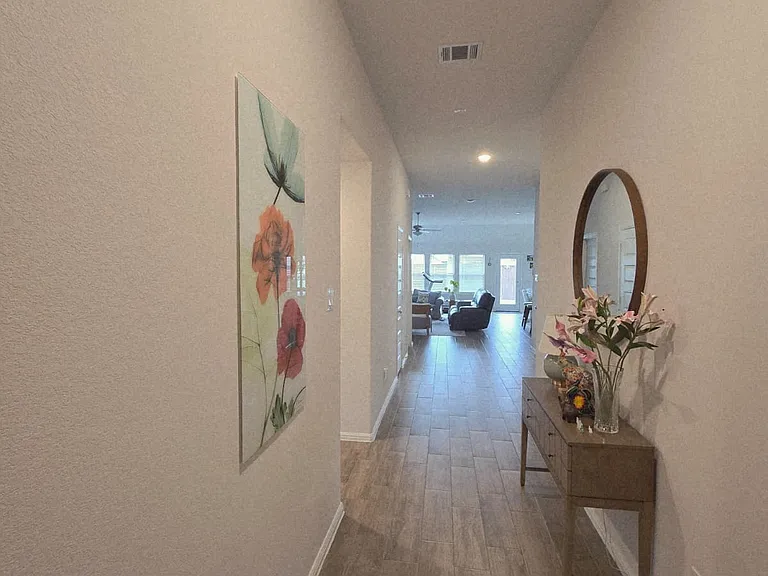Entrance hallway featuring high ceilings, abundant natural light, and elegant ceramic tile flooring throughout. The long, open layout creates a bright and airy feel while connecting the entry to the main living area, offering a stylish first impression.