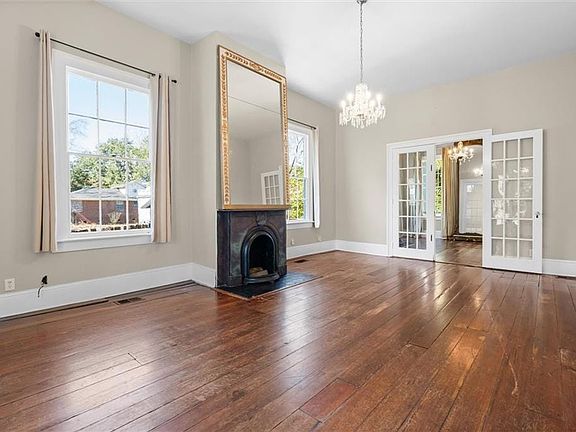 Unfurnished living room featuring french doors, dark hardwood / wood-style floors, and a notable chandelier