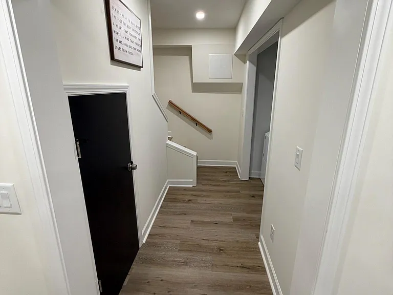 Clean hallway and stair landing with durable wood-look flooring, neutral walls, and easy access to adjacent rooms.