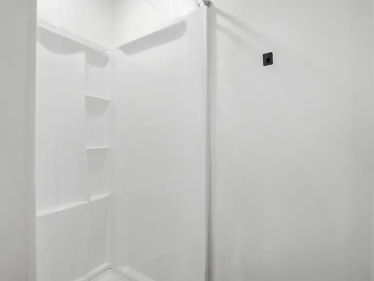 Clean, easy-care tub/shower combo with built-in shelving for toiletries and a simple, functional layout.
