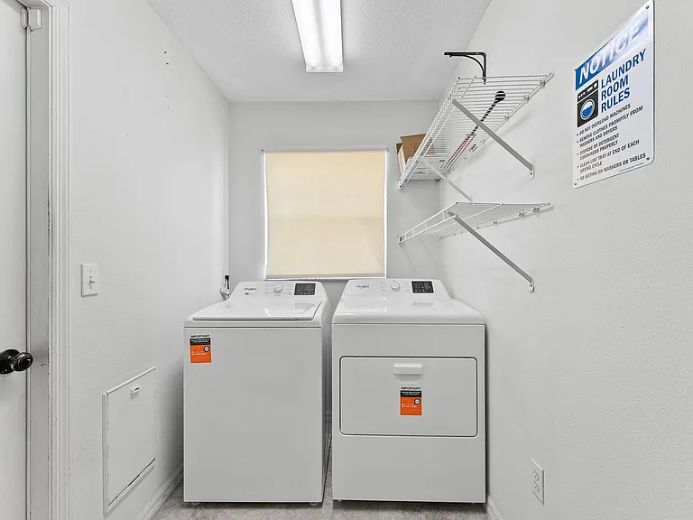 Dedicated laundry room with washer and dryer, plus wall-mounted shelving and a window for added ventilation.