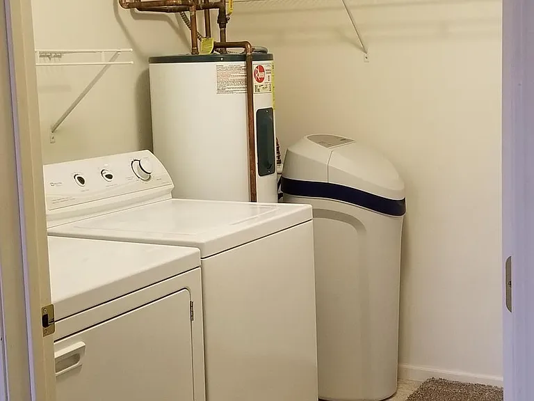 Walk-in closet has washer, dryer, large water heater, and water softener