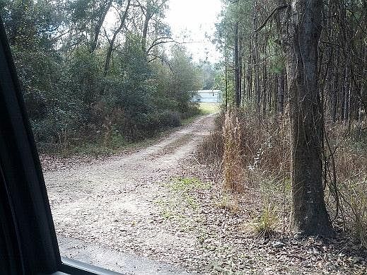 Secluded driveway entrance off of a paved road.
