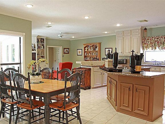 The east wing of the house is where the family or your guests can gather around the cooks in the large kitchen, or sit at the bar or breakfast room table .