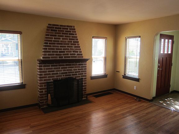 Sunny living room with wood-burning fireplace and hardwood floors