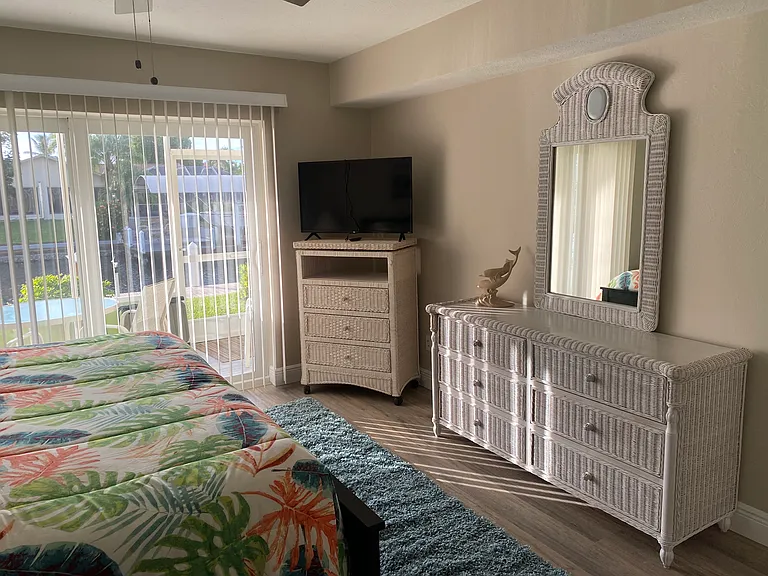 Master bedroom dressers and TV with sliders leading to lanai. Ample storage