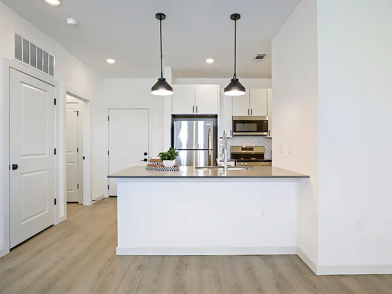 Chef-ready kitchens feature white shaker cabinets, herringbone tile backsplash, stainless steel appliances, and stylish pendant lighting. Garrett Harvest Junction West, Longmont, CO.