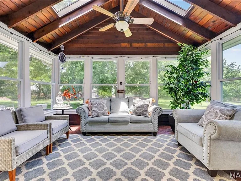 Enclosed patio featuring a wood-finish vaulted ceiling with skylight, white siding walls, and multiple large windows