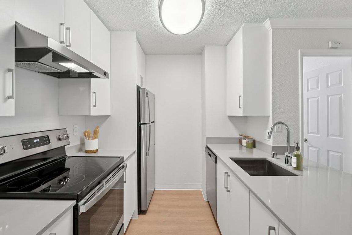 Renovated Package I kitchen with white cabinetry, grey quartz countertops, and hard surface flooring